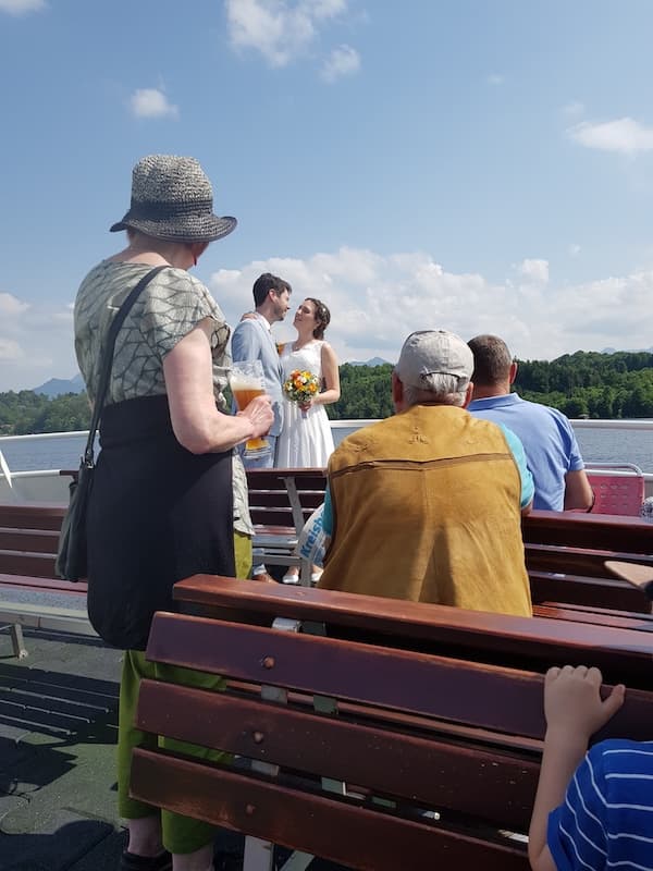 Ein Gast fotografiert das Brautpaar zwischen den Hochzeitsgästen auf einem Schiff