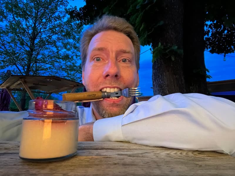 Ein Gast macht am Gartentisch ein Selfie mit einer Gabel quer im Mund